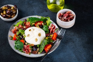 Burrata, krema ve inek sütünden yapılmış İtalyan taze peyniri. Domatesli ve salatalı Burrata salatası. Sağlıklı beslenme konsepti. Keto diyet salatası