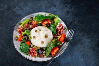 Burrata, krema ve inek sütünden yapılmış İtalyan taze peyniri. Domatesli ve salatalı Burrata salatası. Sağlıklı beslenme konsepti. Keto diyet salatası