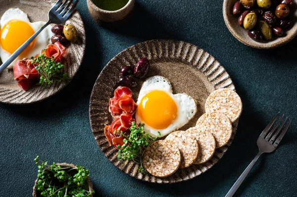 Romantic breakfast - fried eggs in the shape of a heart and olives. Healthy breakfast. Rice cakes with eggs and hamon. Keto diet breakfast. Top view