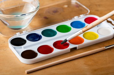 Boya fırçaları palet ve beyaz kağıtla suluboya boyalar. Sanatçı işyeri.