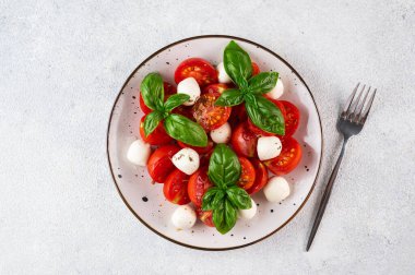 Dilimlenmiş domatesli İtalyan caprese salatası, mozzarella, fesleğen, koyu arkaplanda zeytinyağı. Üst Manzara. İtalyan yemeği. Sağlıklı salata. Yaz yemeği.