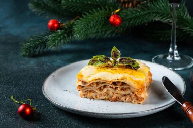 Hafif arka planda lezzetli bir lazanya parçası. Geleneksel İtalyan lazanyası. İtalyan yemeği. Lazanyayı kapat. Yılbaşı dekorlu lazanya. Hala yiyecek dolu bir hayat. Ev yapımı makarna.