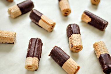 Çikolata kaplı waffle ruloları beyaz masada, yatay hayat