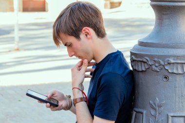 Sokakta akıllı telefonuna dikkatle bakan düşünceli bir beyaz adam.