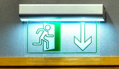 Duvarda yanan yeşil çıkış ışığı tabelası var. Kapat.