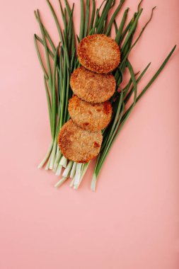 Pembe arka planda yeşil taze soğanlar. Hamur köftesi üstüne serilmiş. Yüksek kalite fotoğraf