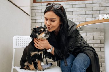 Güzel bir manken sokakta bir kafede siyah bir köpekle yemek yiyor. Sevgiler, sevgiler. Hafif arkaplan. Yüksek kalite fotoğraf