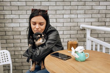 Güzel bir manken sokakta bir kafede siyah bir köpekle yemek yiyor. Sevgiler, sevgiler. Hafif arkaplan. Yüksek kalite fotoğraf