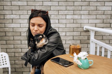 Güzel bir manken sokakta bir kafede siyah bir köpekle yemek yiyor. Sevgiler, sevgiler. Hafif arkaplan. Yüksek kalite fotoğraf