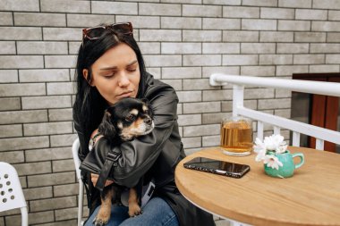 Güzel bir manken sokakta bir kafede siyah bir köpekle yemek yiyor. Sevgiler, sevgiler. Hafif arkaplan. Yüksek kalite fotoğraf