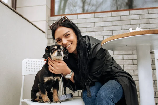 美少女モデルは黒犬と一緒に路上のカフェで食事をします 光の背景 高品質の写真 — ストック写真