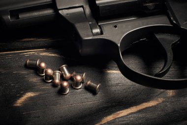 Üzerinde Flobert mermisi olan siyah tabanca. Koyu tahta arka planda 4mm.