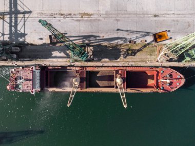 kargo gemisi gün batımında limana yükleniyor, hava görüntüsü
