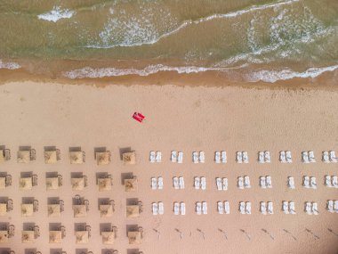 Yaz günü saman plaj şemsiyeleri ve turkuaz berrak suyla muhteşem boş bir kumsal manzarası..