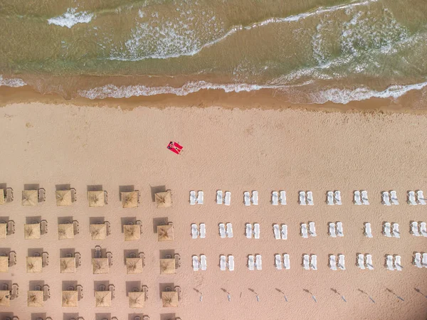 Yaz günü saman plaj şemsiyeleri ve turkuaz berrak suyla muhteşem boş bir kumsal manzarası..