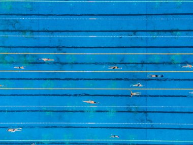 Yüzme havuzunda yüzme eğitimi alan bir grup yüzücünün hava görüntüsü. Birçok sportif insan açık deniz yüzme havuzunda yüzer..