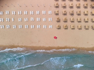 Yaz günü saman plaj şemsiyeleri ve turkuaz berrak suyla muhteşem boş bir kumsal manzarası..