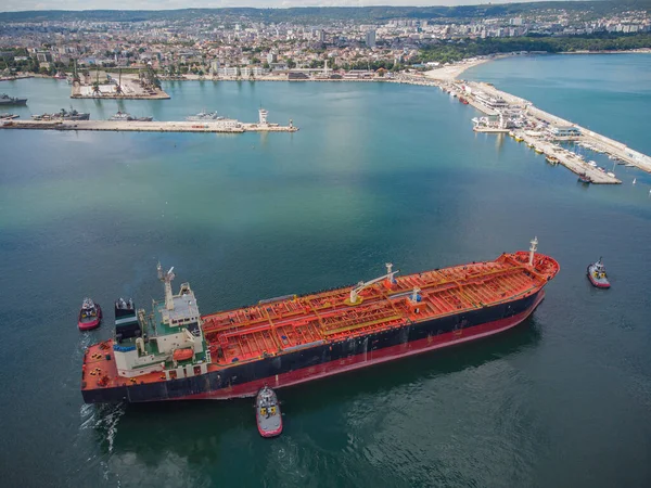 Aerial top view of tanker ship with escorting tug leaving port