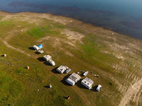 Aerial top view of a campers van parked on a beach, mountain range landscape
