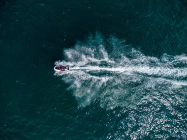 Aerial top down view of floating scooter on blue sea at sunny day.