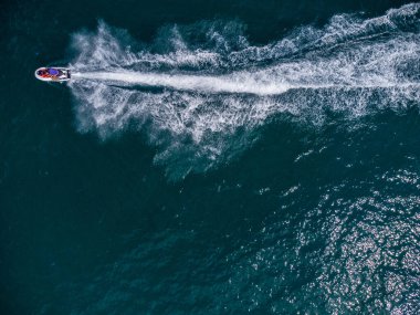 Aerial top down view of floating scooter on blue sea at sunny day.