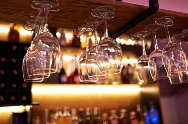 Closeup wine glass on rack above blurred bar background