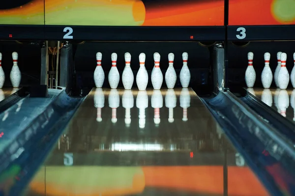 White bowling pins reflecting in bowling alley lane