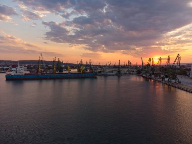 Aerial view of big cargo ship bulk carrier is loaded with grain of wheat in port at sunset