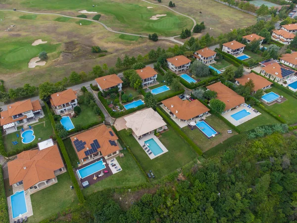 Modern cottage village with luxury houses, swimming pools and golf courses aerial top view.