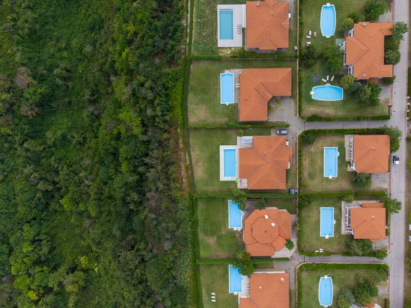Modern cottage village with luxury houses, swimming pools and golf courses aerial top view.