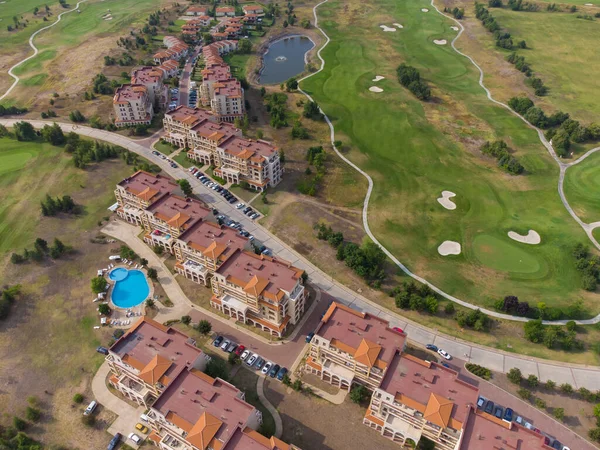 Modern cottage village with luxury houses, swimming pools and golf courses aerial top view.