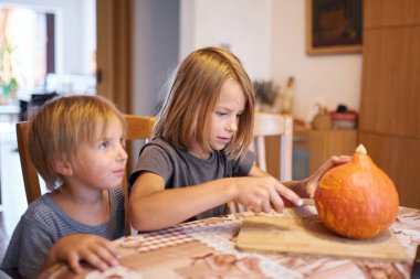 Young kids carving Halloween pumpkin at home