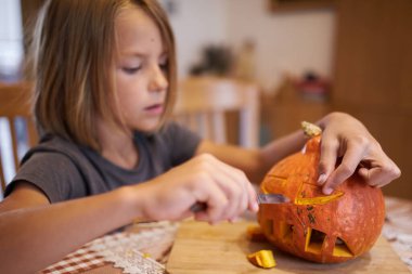 8 year old boy carving Halloween pumpkin at home