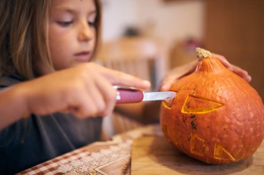 8 year old boy carving Halloween pumpkin at home