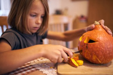 8 year old boy carving Halloween pumpkin at home