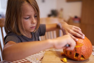 8 year old boy carving Halloween pumpkin at home