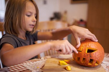 8 year old boy carving Halloween pumpkin at home