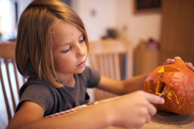 8 year old boy carving Halloween pumpkin at home
