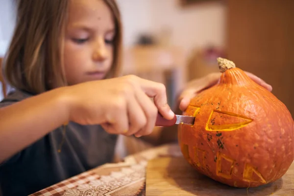 8 year old boy carving Halloween pumpkin at home