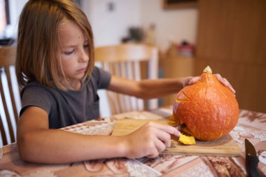 8 year old boy carving Halloween pumpkin at home