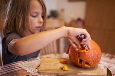 8 year old boy carving Halloween pumpkin at home