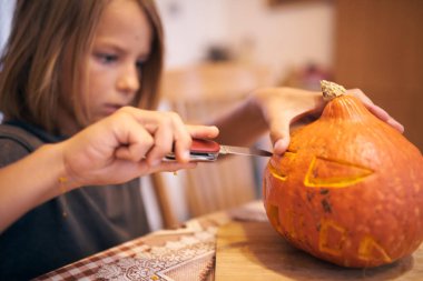 8 year old boy carving Halloween pumpkin at home