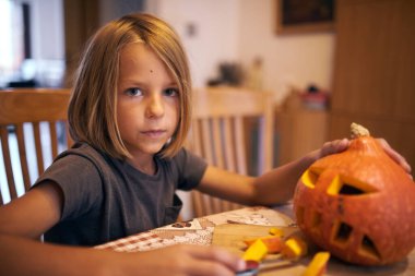 8 year old boy carving Halloween pumpkin at home