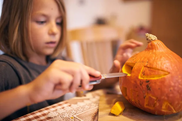8 year old boy carving Halloween pumpkin at home