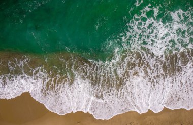Kumlu bir plajda, deniz manzaralı, tepeden aşağıya insansız hava aracı.