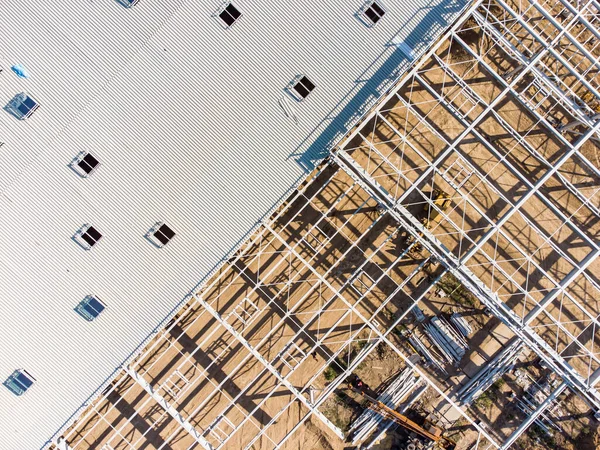 Aerial top view of warehouse construction from steel metal structure. Frame of modern hangar or factory construction site.