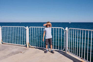 8 yaşında bir çocuk güneşli bir günde rıhtımda