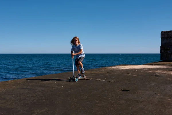 Güneşli Bir Günde Iskelede Scooter Süren Bir Çocuk — Stok fotoğraf