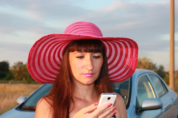 Attractive girl looks into the phone — Stock Photo, Image