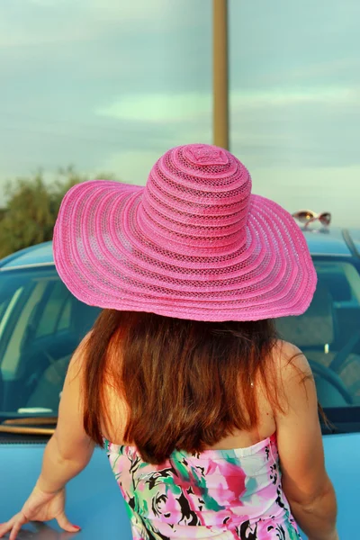 Pitkätukkainen nainen seisoo auton takana — kuvapankkivalokuva